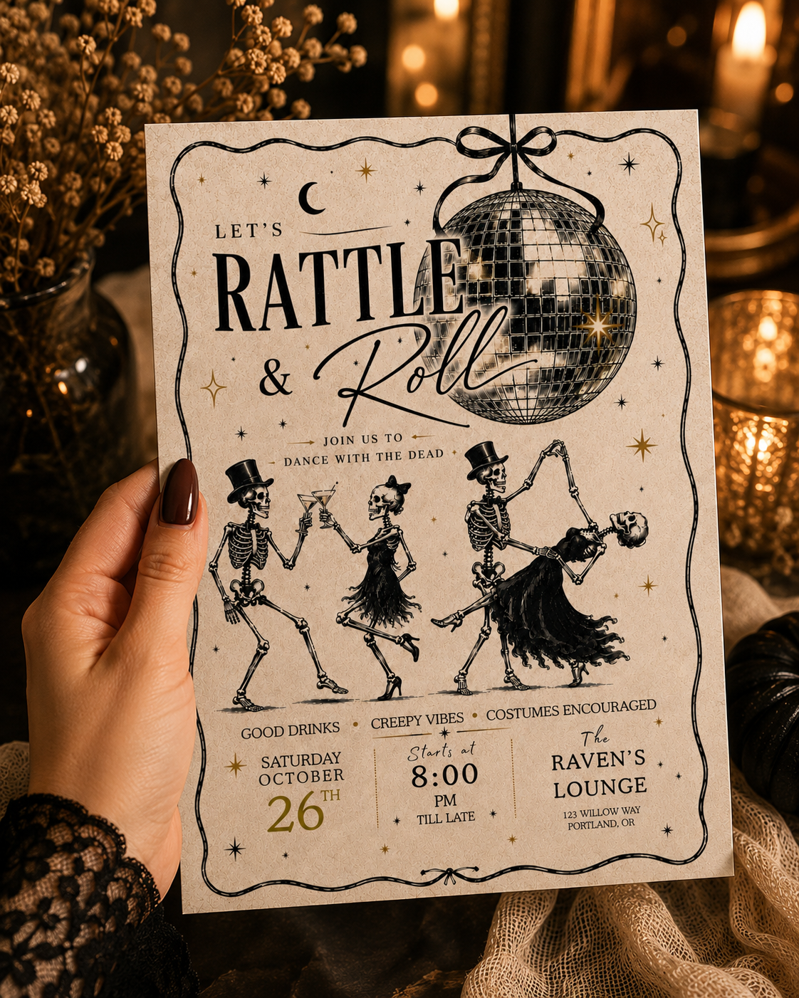 A hand holds a vintage-style Halloween invitation card featuring skeleton dancers, a disco ball, and text reading 'Let's Rattle & Roll' and 'The Raven's Lounge.' The background is a warm, blurred festive setting with candles and dried flowers.