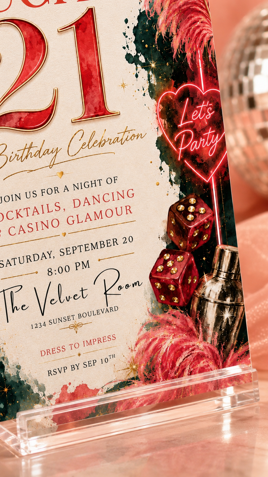 A close-up of a themed birthday invitation card on a clear acrylic stand, featuring red neon-style text, dice, feathers, and a cocktail shaker on a pink and warm-toned background.