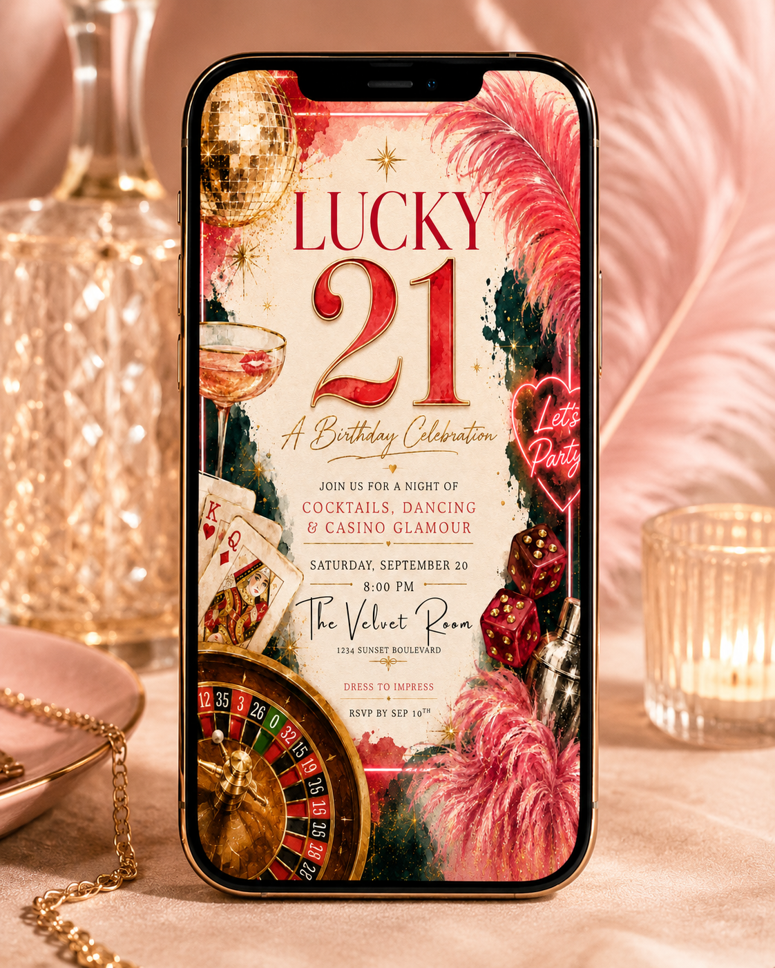 A smartphone displaying a festive 'Lucky 21' birthday invitation design, styled on a beige fabric surface with a gold chain, glassware, and pink feathers in the background.