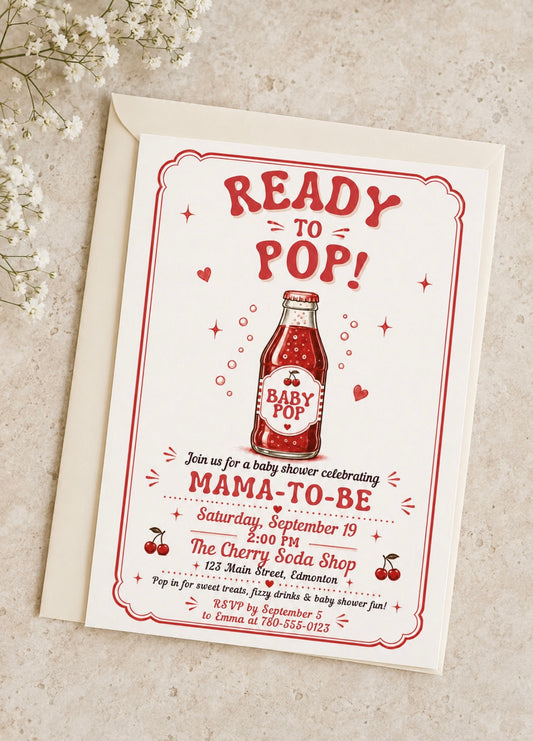 A baby shower invitation card with an envelope, featuring a retro red and black 'Ready to Pop! Mama-to-be' design with a cherry soda bottle illustration, photographed on a light textured surface with small white flowers in the corner.